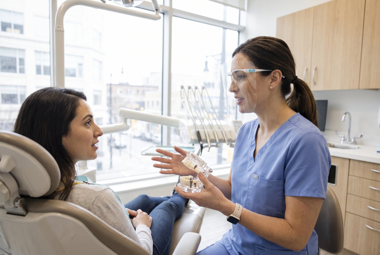 Reseda dentist using a jaw model to explain how a dental implant integrates with bone to a seated patient