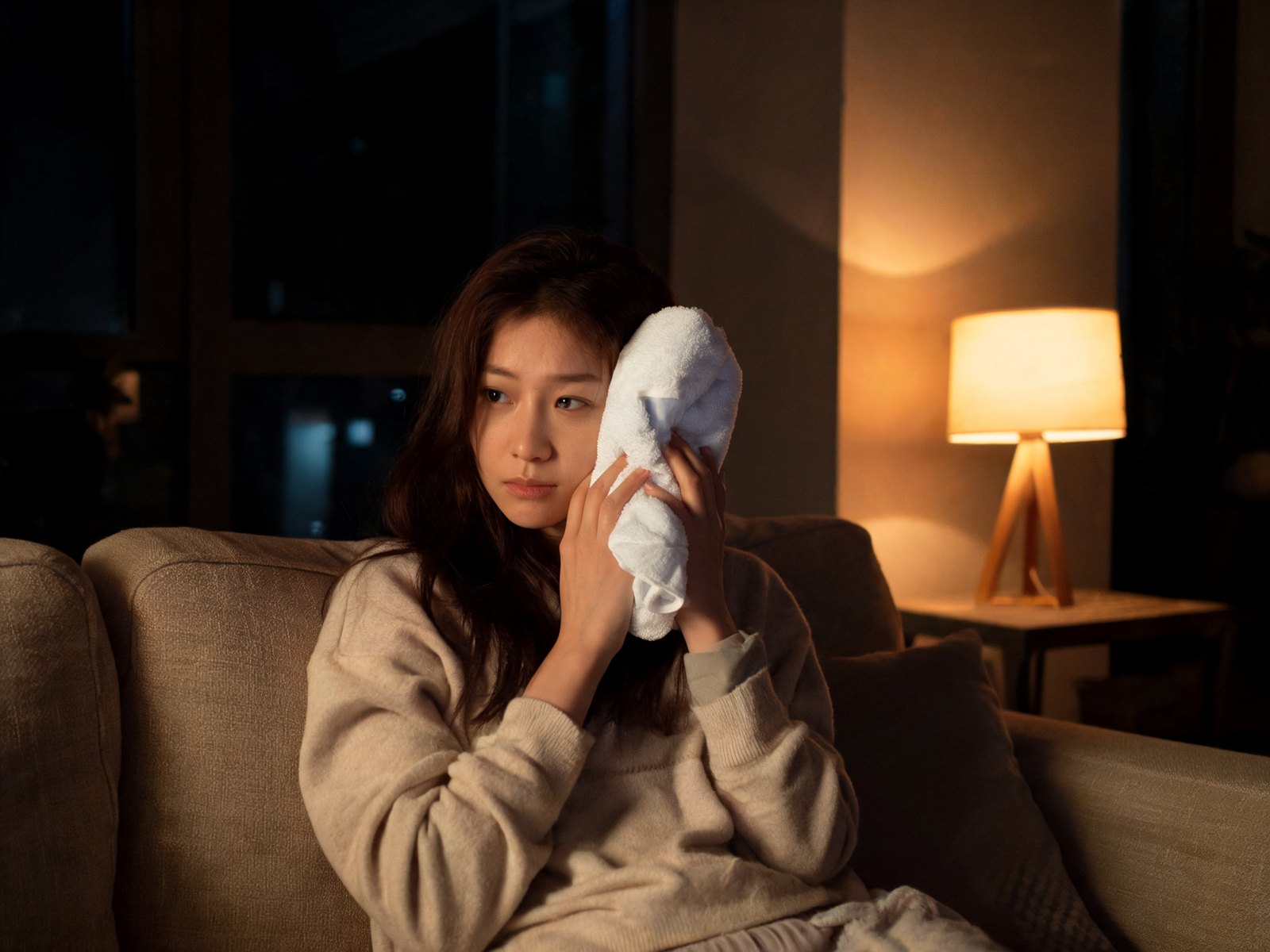 Woman holding a cold pack against her cheek at night