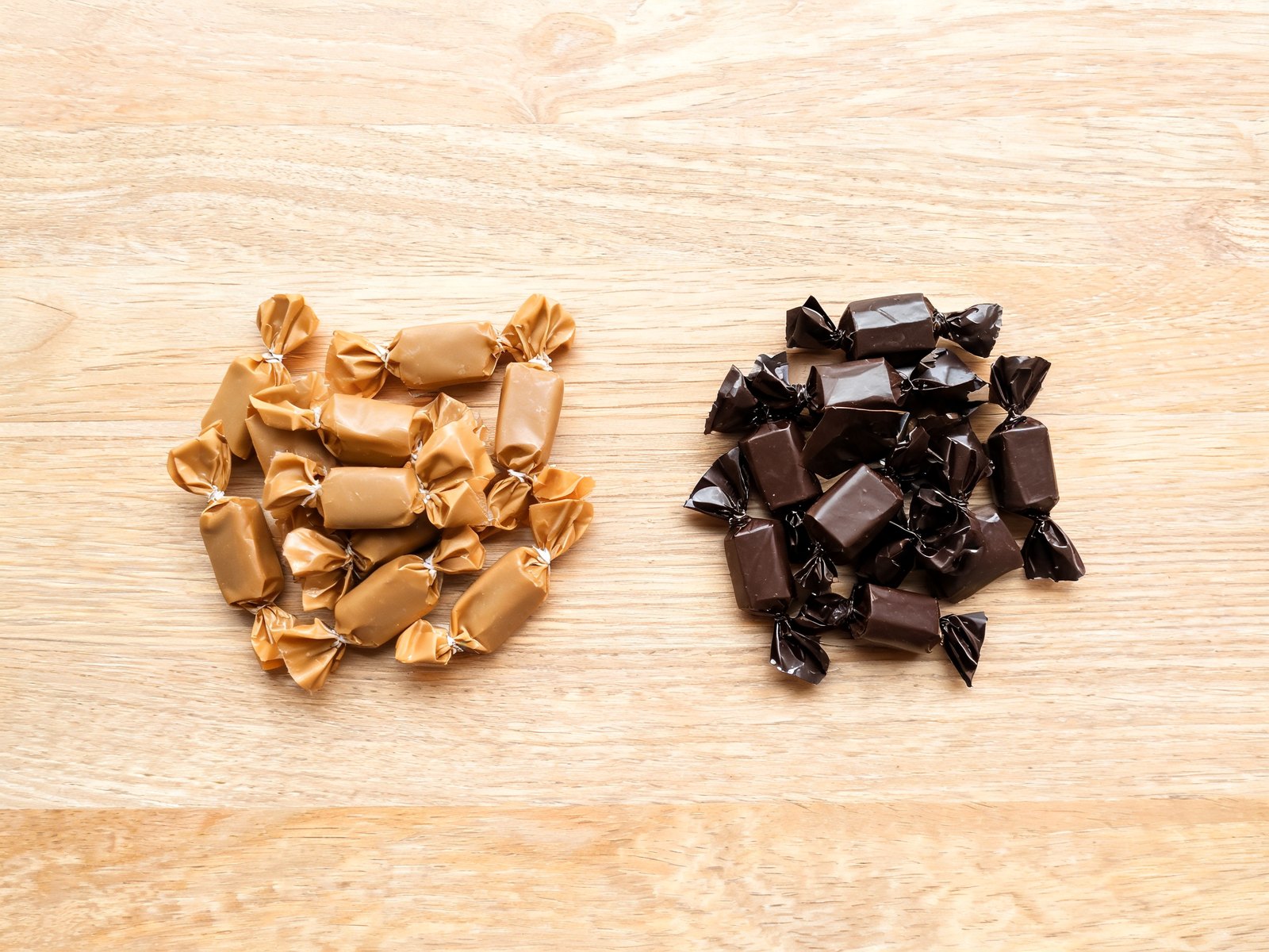 Wrapped candies sorted into chewy caramels and small chocolates on a table